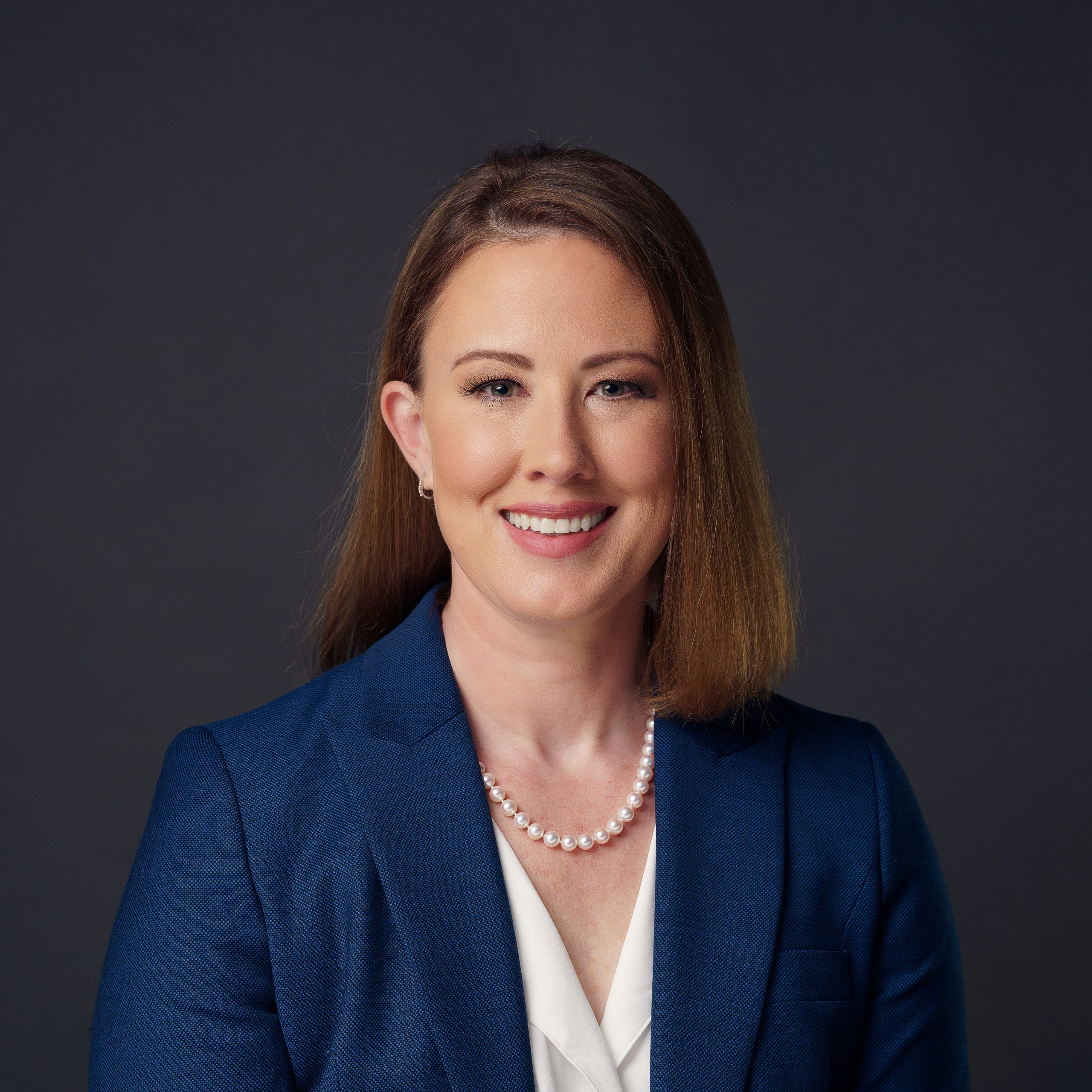 Image of corporate women in navy blue smiling for a professional headshot.